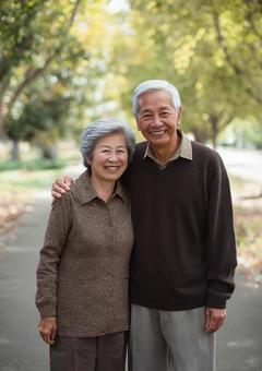 並木道を歩く笑顔のシニア夫婦の写真