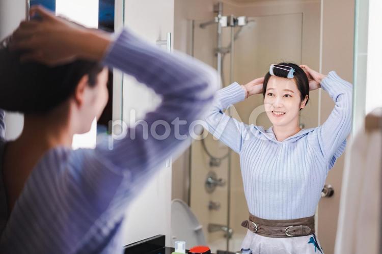 鏡の前で髪のセットをする若い女性 若い,髪の毛,アイロンの写真素材