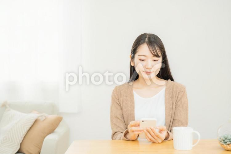 家でスマホを使う女性 スマホ,スマートフォン,笑顔の写真素材