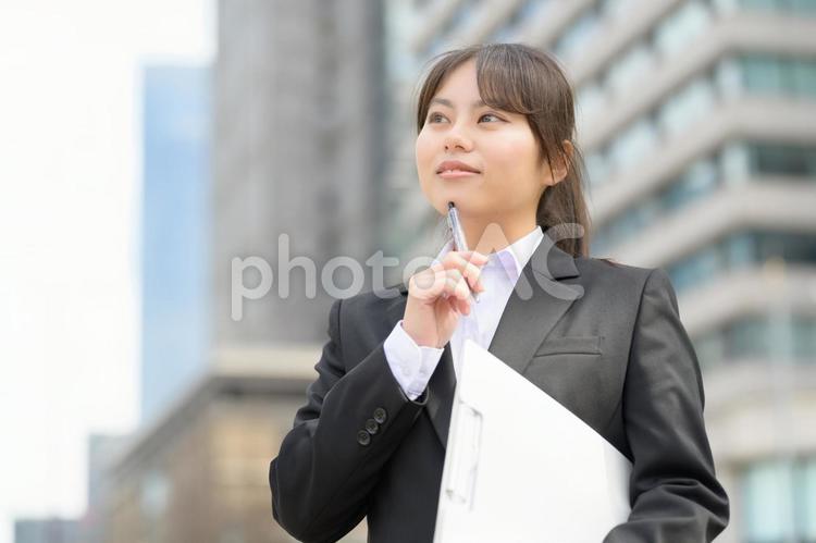 屋外でバインダーを持って悩むスーツの女性 日本人,女性,新入社員の写真素材