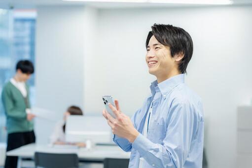 オフィスでスマホを使うビジネスマン スマホ,ビジネスマン,笑顔の写真素材
