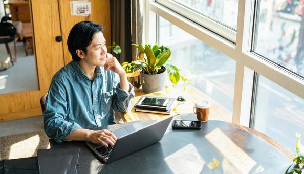 カフェで仕事をするフリーランス男性 カフェで仕事をするフリーランス男性の写真
