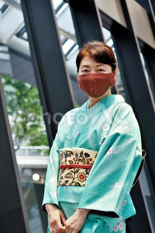 デザインティックなオフィスビルの無料開放広場に立ってこちらを見つめる着物の女性 着物,和服,女性の写真素材