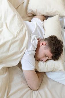 ベッドでうつ伏せで寝ている男性 男性,外国人,欧米人の写真素材