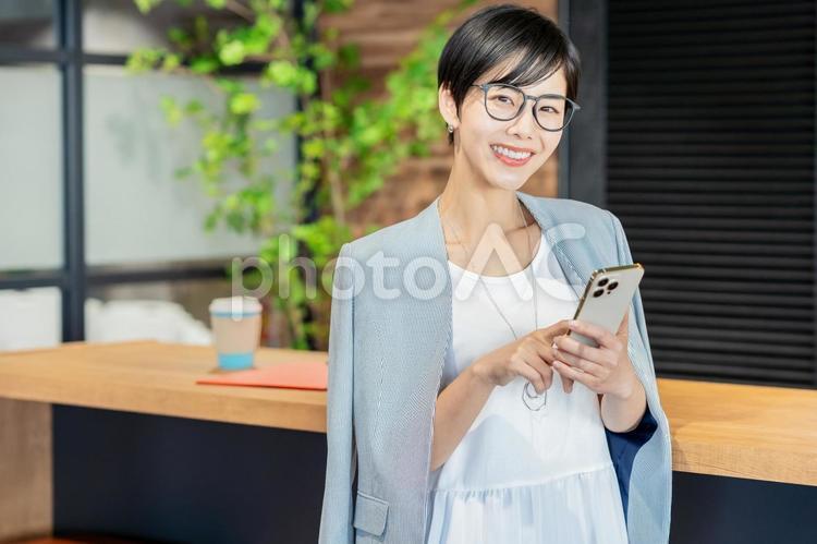 オフィスでスマホを持つビジネスウーマン スマホ,若い女性,女性の写真素材