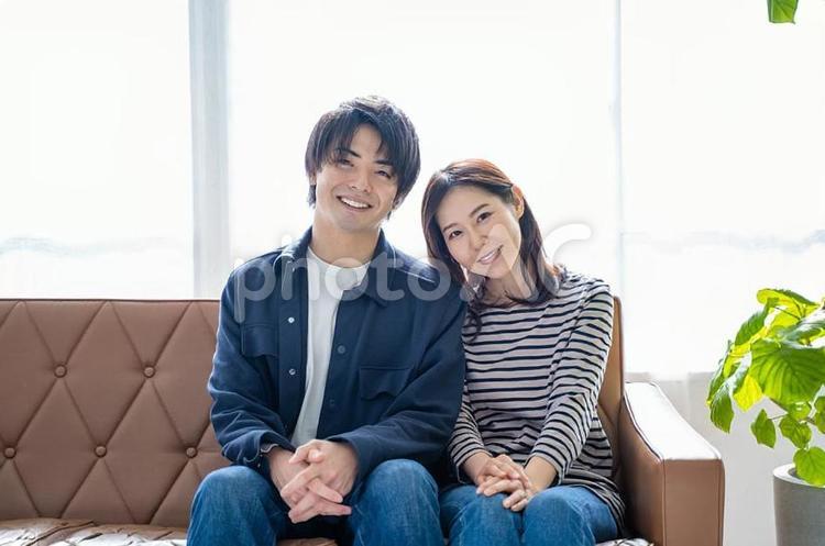ソファに座り微笑む夫婦-明るい観葉植物 夫婦,ソファ,リラックスの写真素材