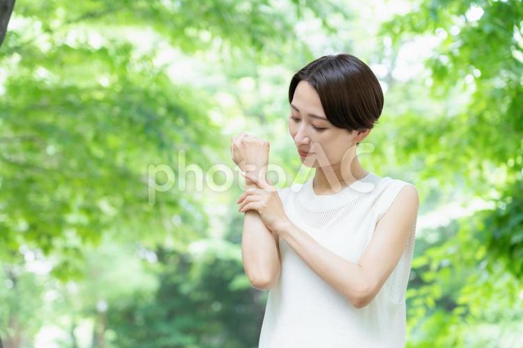 新緑の中でスキンケアをするミドルの女性 ビューティー,女性,スキンケアの写真素材