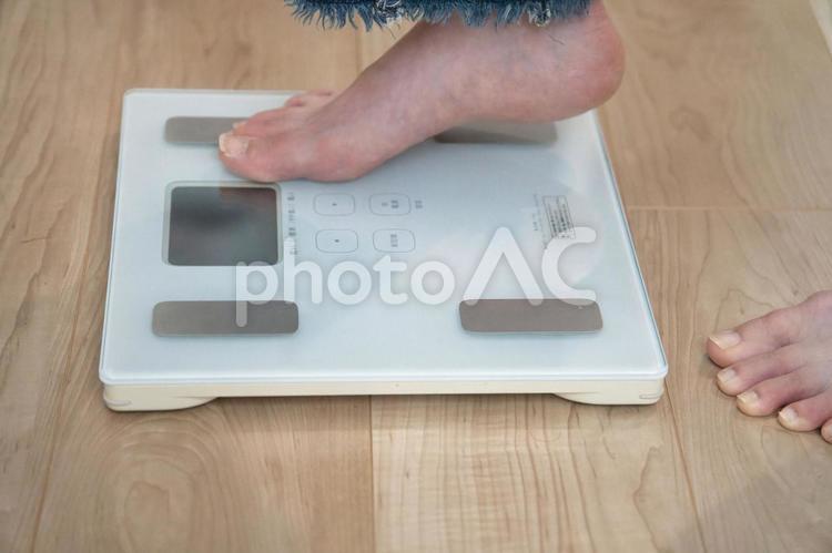 リビングで体重計にそっと足を乗せる女性 体重計,体重管理,健康維持の写真素材