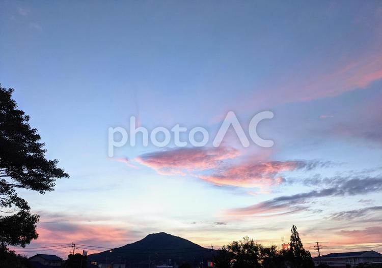 青空の夕焼け雲が美しいピンク色に染められ山や樹木を黒いシルエットに浮かび上がらせている 青空,青,空の写真素材