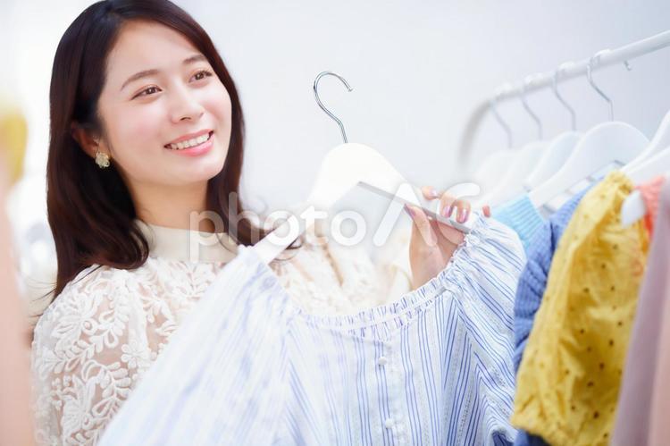 ストライプ柄の服を持つ笑顔の女性 女性,服,ハンガーの写真素材