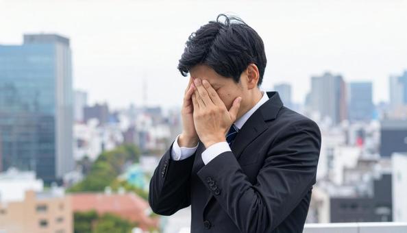 オフィスビルの屋上で苦悩するビジネスマン オフィスビルの屋上で苦悩するビジネスマンの写真