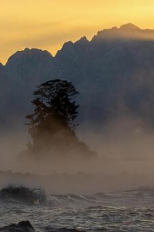 気嵐の女岩｜波しぶき｜剱岳に朝日｜縦 雨晴海岸,女岩,気嵐の写真素材