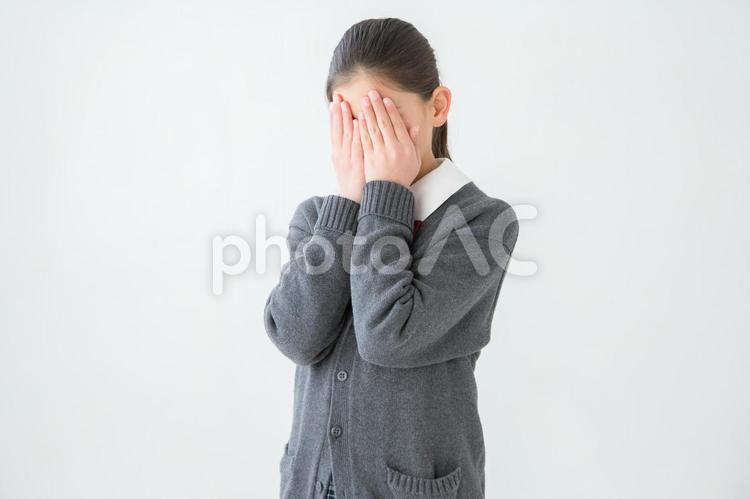 顔を隠す女子学生 泣く,いじめ,制服の写真素材