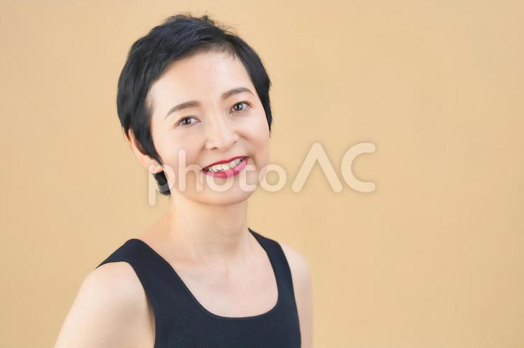 笑顔でカメラ目線のショートカットの女性（ベージュ背景） 女性,日本人,50代の写真素材