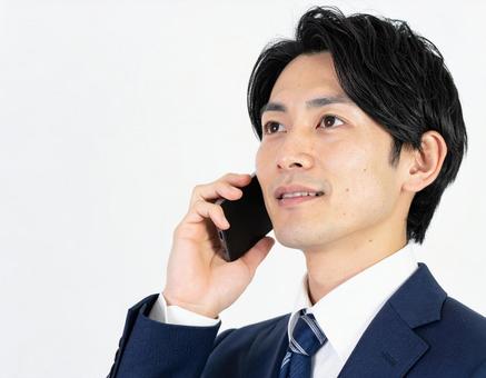 携帯電話で通話する若いビジネスマン 携帯電話で通話する若いビジネスマンの写真