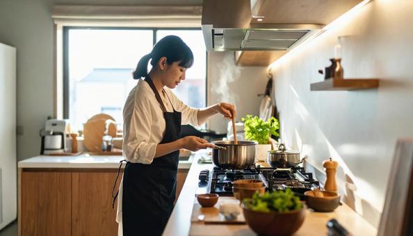 モダンなキッチンで料理をしている若い女性 モダンなキッチンで料理をしている若い女性の写真