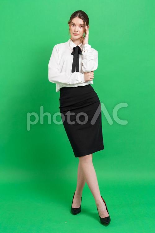 こめかみに手を当てる女性（緑背景） 女性,立つ,ポーズの写真素材