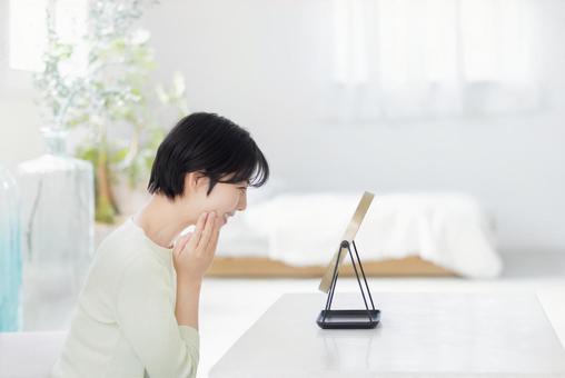 リビングでスキンケアをする女性 リビングでスキンケアをする女性の写真