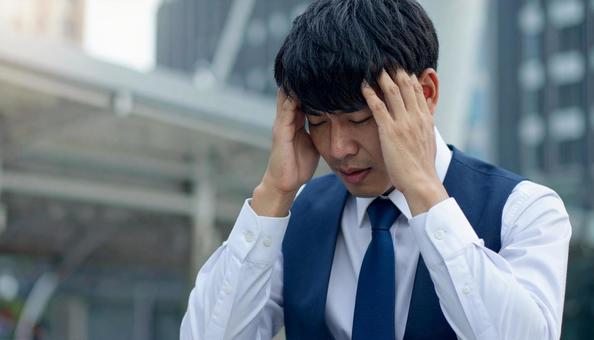 頭を押さえて悩む男性ビジネスマン 頭を押さえて悩む男性ビジネスマンの写真