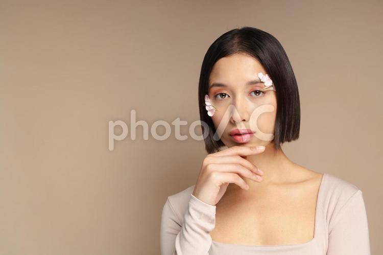 顎を触りカメラ目線のボブの女性 女性,フラワーメイク,花びらの写真素材