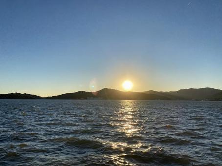 風が強く吹く湖の対岸の山に夕陽が沈む 湖,雲,初夏の写真素材