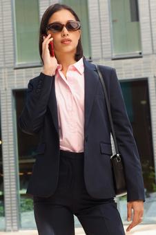 オフィスビルの外で電話するサングラスを掛けたビジネスウーマン ビジネスウーマン,ビジネス,女性の写真素材