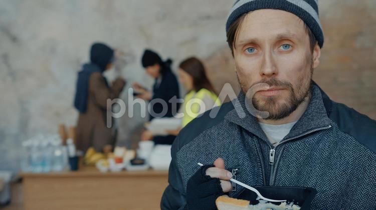 カメラ目線で炊き出しを食べる男性 男性,ニット帽,人物の写真素材