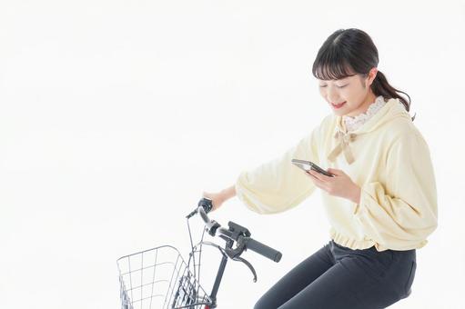 自転車でスマホを使う若い女性 自転車でスマホを使う若い女性 地図,スマホ,保険料の写真素材