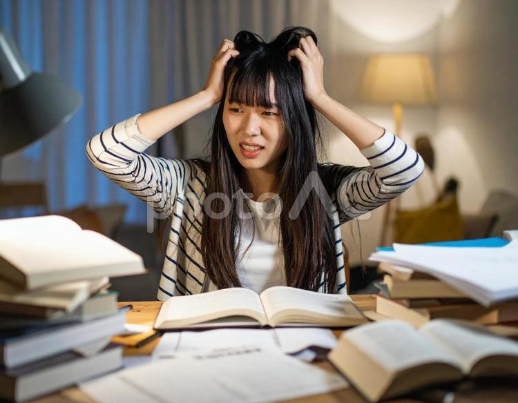 机で勉強中に頭を抱える女子学生 女性,学生,勉強の写真素材
