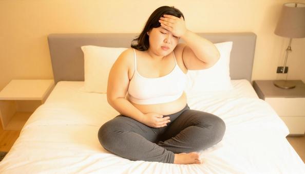 肥満で疲れやすく、額に手をやる女性 肥満で疲れやすく、額に手をやる女性の写真