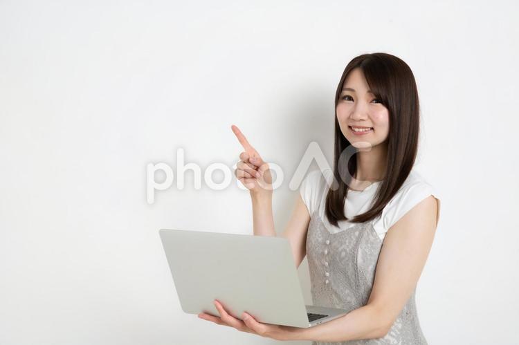 パソコンを持って指差ししている若い女性（コピースペース） 女,女性,女の子の写真素材
