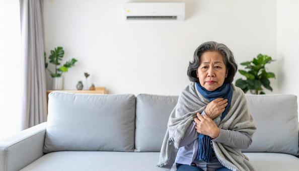 冷房が強すぎて寒がる体調不良のシニア女性の写真