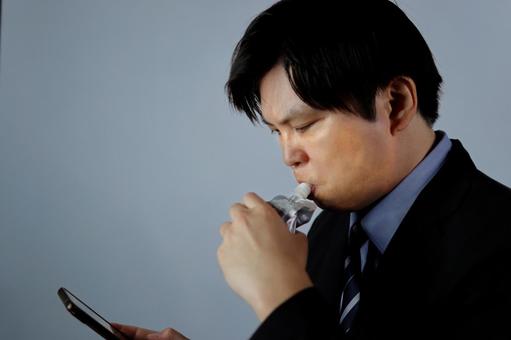 スマホを見ながら飲む男性 男性,ビジネスマン,スーツの写真素材