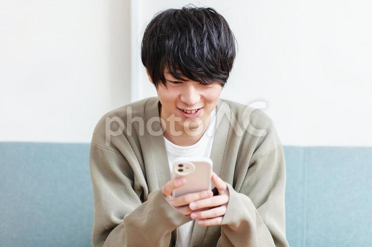 笑顔でスマホを操作する男性　 男性,スマホ,携帯電話の写真素材