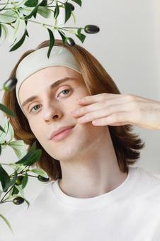 頬を触っているカメラ目線のヘアバンドをした男性 男性,外国人,欧米人の写真素材