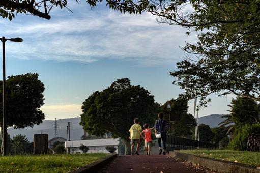 <素材>夕暮れの公園の遊歩道を歩く親子 <素材>夕暮れの公園の遊歩道を歩く親子 家族,兄弟,親子の写真素材