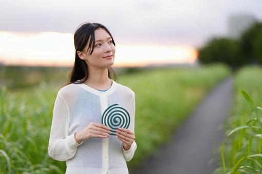 両手で蚊取り線香を持つ女性 女性,蚊取り線香,持つの写真素材