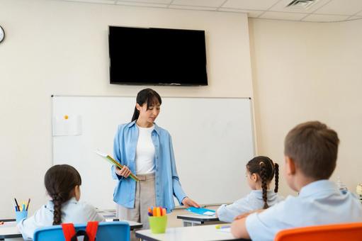 授業をする先生と生徒たちの後ろ姿 女性,女の子,男の子の写真素材