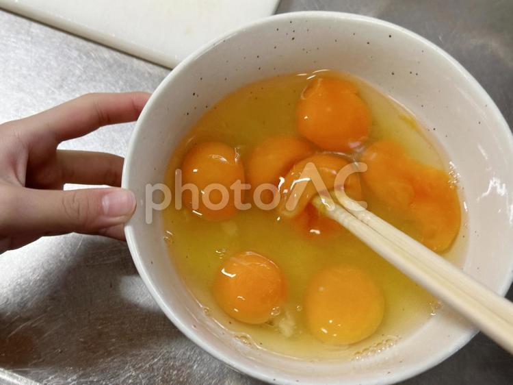 卵を溶いてお手伝いする女の子 卵,混ぜる,手の写真素材