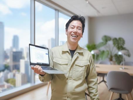 作業服姿の男性が笑顔でノートPCを持つ姿 ビジネスマン,微笑む,微笑みの写真素材