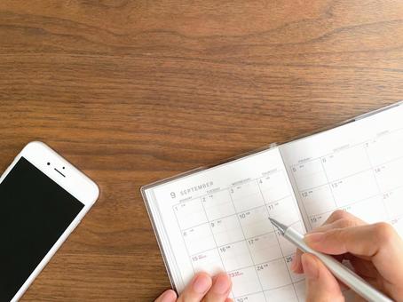 スマートフォンと手帳で予定を記入する手 スマートフォンと手帳で予定を記入する手 スケジュール帳,書く,手の写真素材