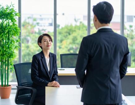 女性上司とその前に立つサラリーマンの部下 女性上司とその前に立つサラリーマンの部下の写真