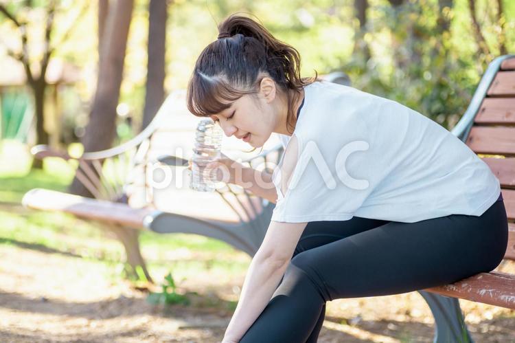 トレーニング中に休憩する女性（膝・足が痛い） 膝,関節痛,ひざの写真素材