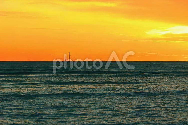 ハワイの海に沈む夕陽とヨットのシルエット ハワイ,夕日,夕焼けの写真素材