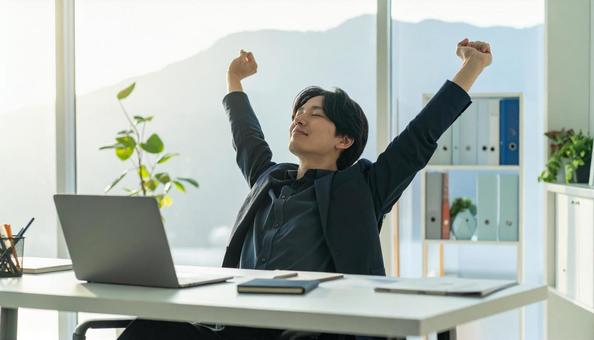 仕事が終わり達成感で背伸びをする社員の写真