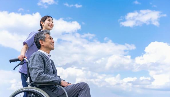 青空の下 同方向を見るシニア男性と介護士 青空の下 同方向を見るシニア男性と介護士の写真