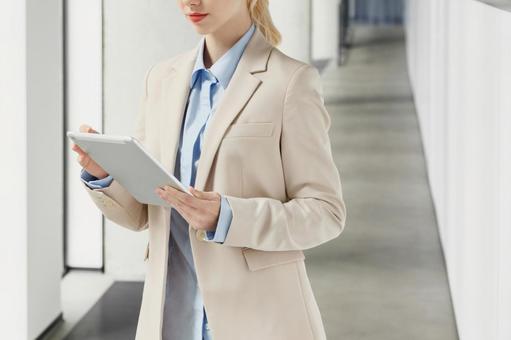 オフィスの通路でタブレットを見る女性 ビジネスウーマン,ビジネス,女性の写真素材
