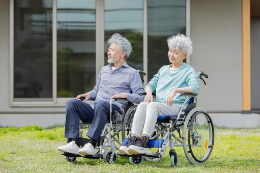 住宅の前で車椅子に乗るシニア夫婦 住宅の前で車椅子に乗るシニア夫婦 車椅子,介護,見上げるの写真素材