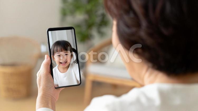 孫とテレビ電話をするおばあちゃん テレビ電話,スマホ,通話の写真素材