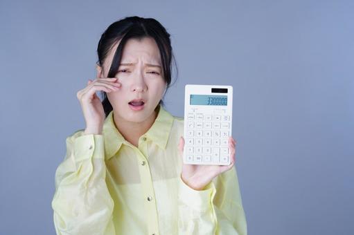 電卓をもって泣きまね黄色い服を着た女性 女性,電卓,持つの写真素材